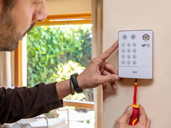 Tecnico instalando alarma de alquiler Técnico instalando el teclado de una alarma de piso en alquiler